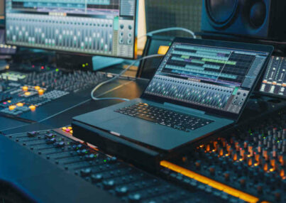 Modern Music Record Studio Control Desk with Laptop Screen Showing User Interface of Digital Audio Workstation Software. Equalizer, Mixer and Professional Equipment. Faders, Sliders. Record. Close-up